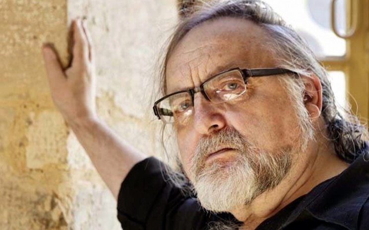 Brian Ferneyhough leaning on a stone wall