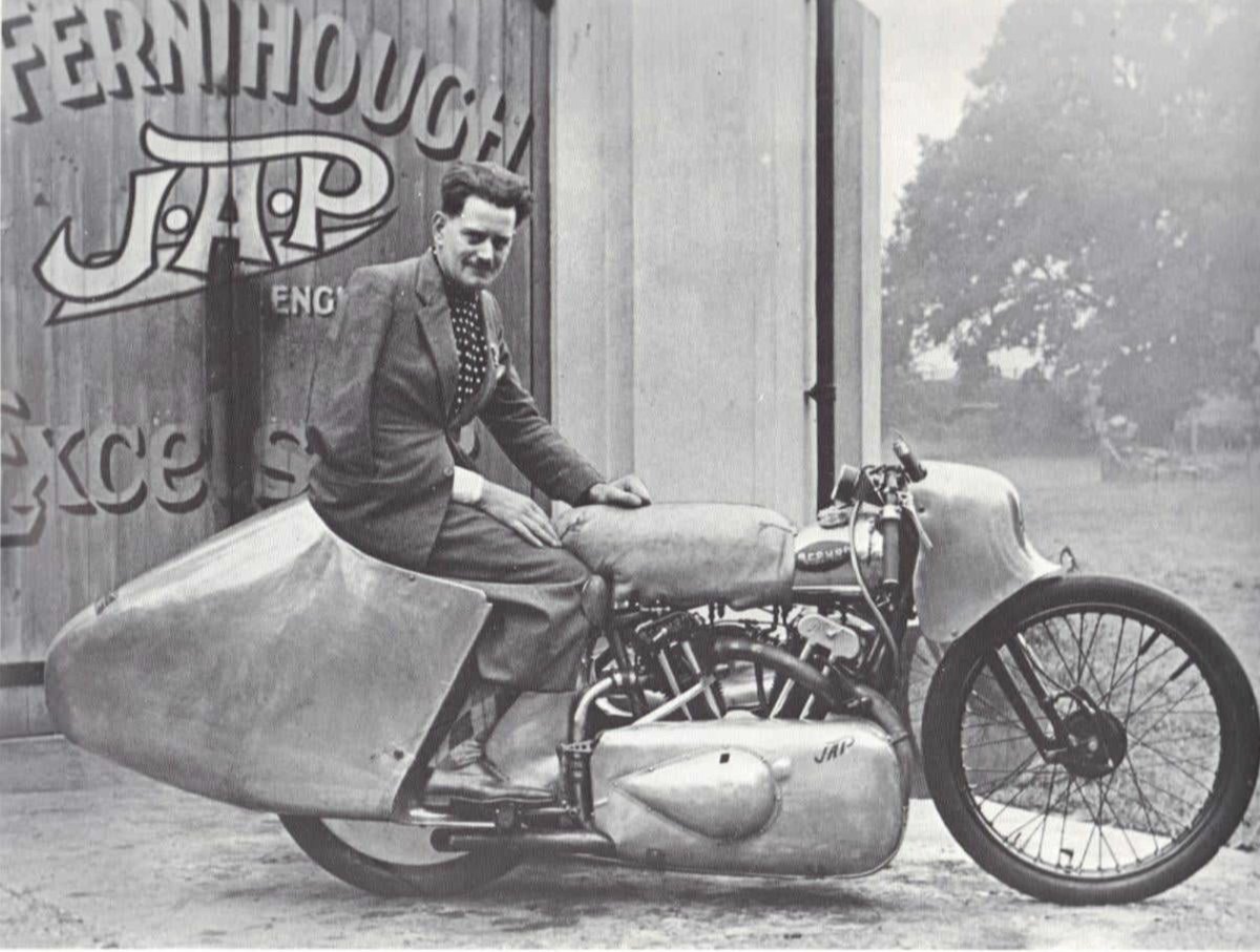 Eric Fernihough seated on his streamlined JAP-engined motorcycle outside a workshop