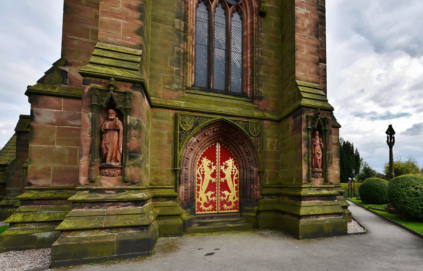 Exterior of St Giles' Catholic Church (Pugin), Cheadle: west tower base with carved saints and red-and-gold lion doors